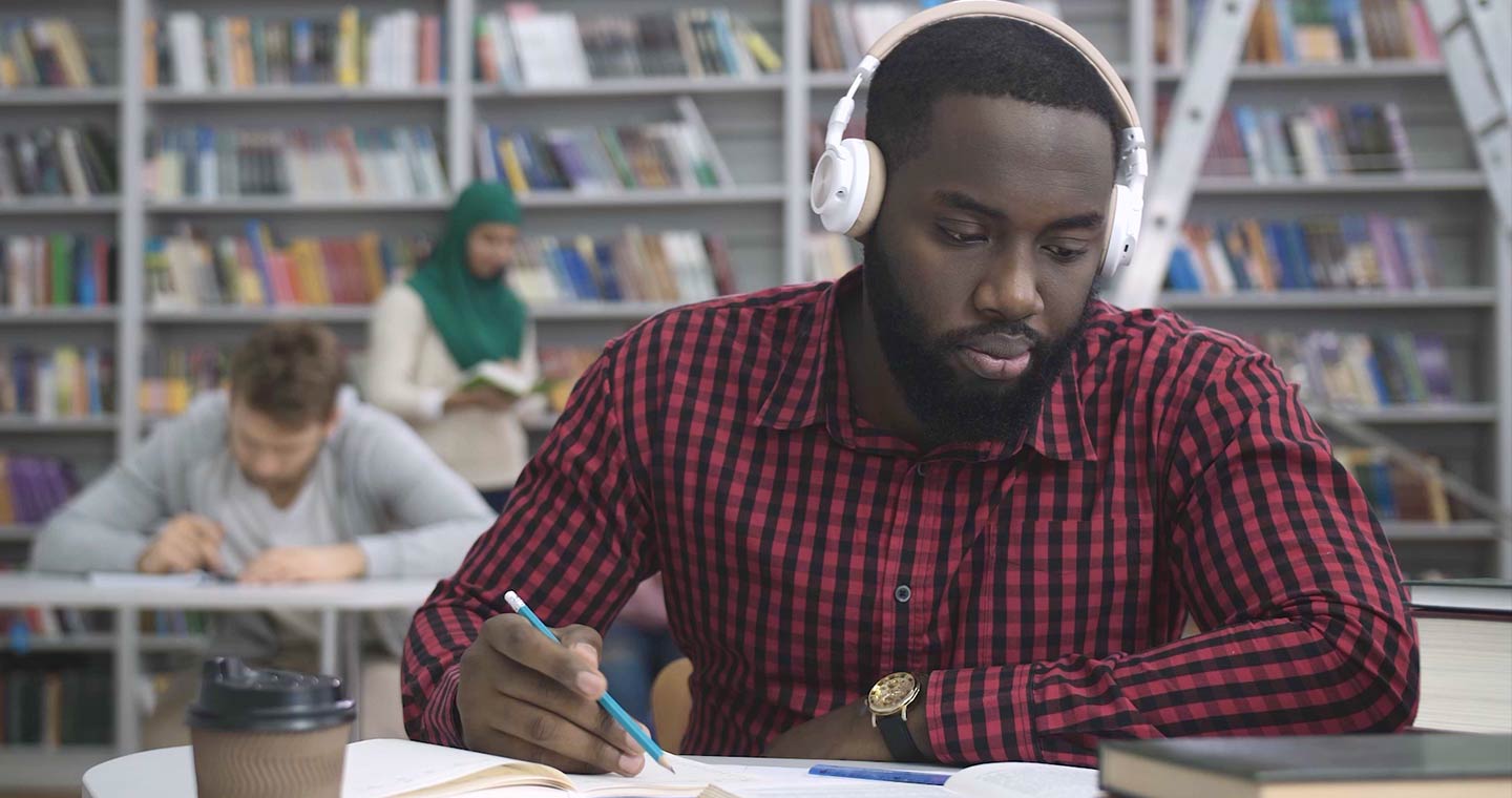 Man in a library with headphones on